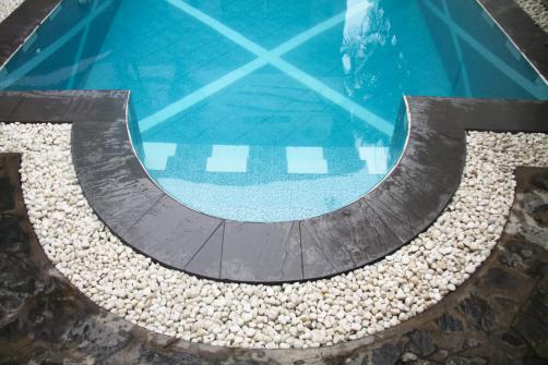 Margelle de piscine en ardoise et cailloux blancs