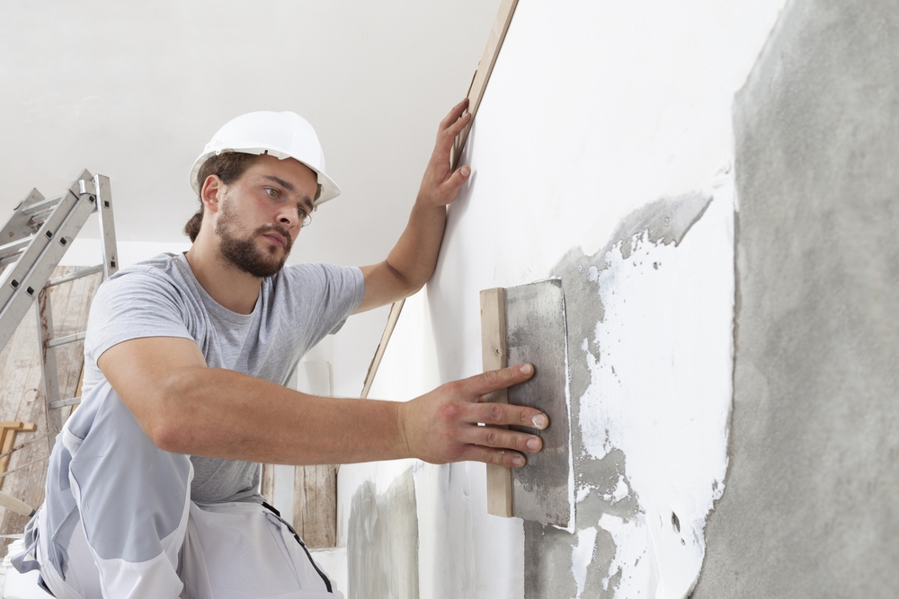 Ouvrier avec une truelle qui plâtre un mur