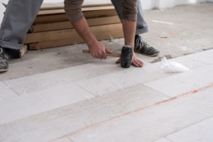 Travailleur installant du carrelage sur du parquet