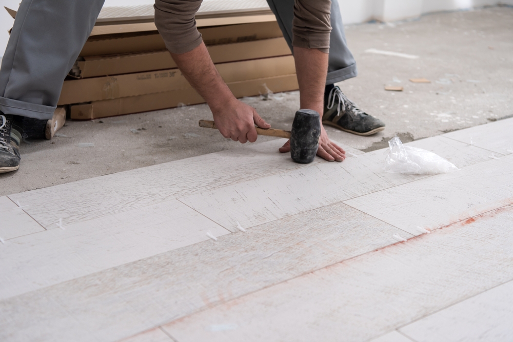 Travailleur installant du carrelage sur du parquet