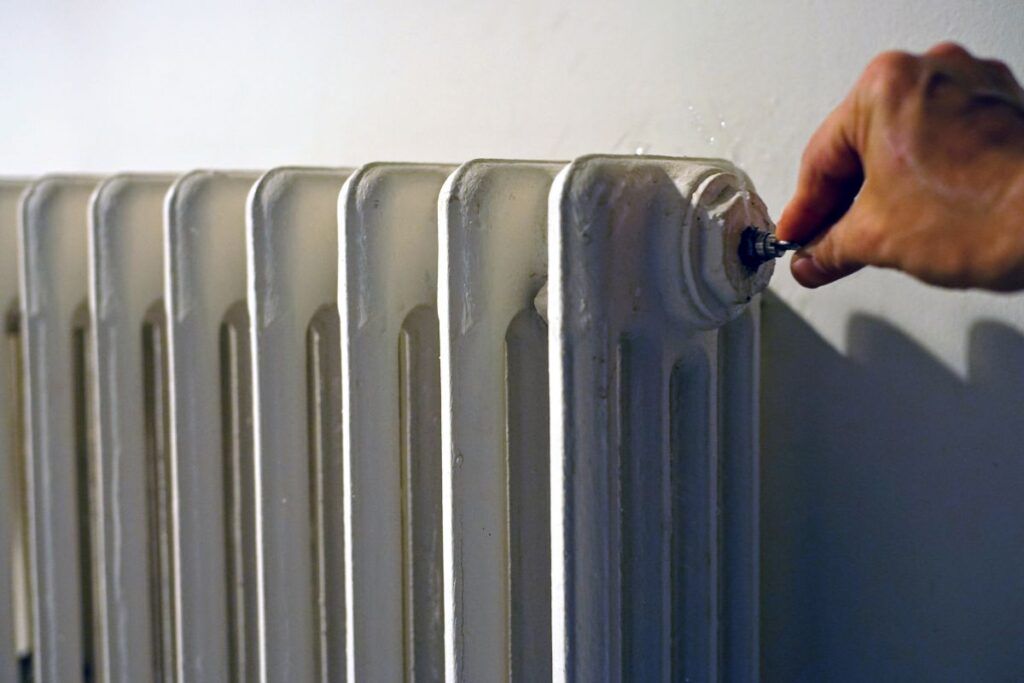 Professionnel qui purge un radiateur en fonte